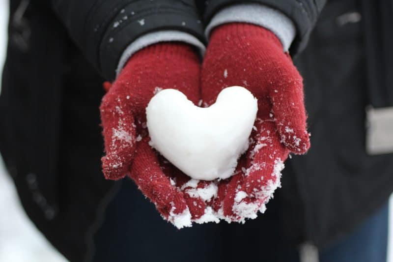 heart-shaped snowball in gloved hands